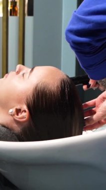 Kısa saçlı ve kısa saçlı güzel bir kız güzellik salonunda bir prosedür uyguluyor. Saç ustası müşterilere saç boyama ve tonu sunuyor. Yüksek kaliteli FullHD görüntüler