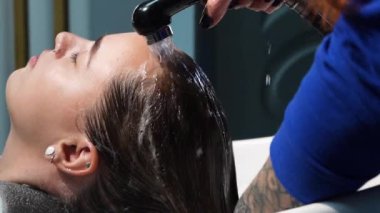 Kısa saçlı ve kısa saçlı güzel bir kız güzellik salonunda bir prosedür uyguluyor. Saç ustası müşterilere saç boyama ve tonu sunuyor. Yüksek kaliteli FullHD görüntüler