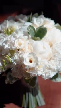 Düğün töreninden önce süslenmiş güzel bir buket beyaz gül. Otel odasında, gelinlerin düğün töreninden önce giydikleri lüks gelinlik. Sabah hazırlıkları...