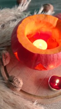 Cadılar bayramında balkabağı balkabağı parlar. Koyu arkaplanda portakal suyu ve balkabağı. Masada mumlar var. Hayaletler, korkular ve ruhlar bayramı için dekor. Yüksek kaliteli FullHD görüntüler