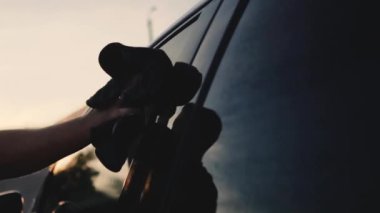 Erkek sürücü, oto yıkamada bir bez parçasıyla arabasını yıkıyor.