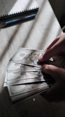 Masaya yakın plan 100 dolarlık banknotlar. Yatırım ve iş için para dolu cüzdan. Yatırımcı ve bankacı birikimlerini sayıyor