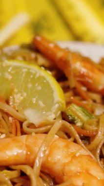 Çin Yeni Yılı. Erişteli karides ve etli Asya mutfağı. Tatil için akşam aile yemeği. Mutluluk ve iyilik için kırmızı zemin üzerinde hiyeroglifler olan altın sikkeler, yelpaze ve kartlar.