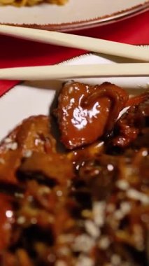 Çin Yeni Yılı. Erişteli karides ve etli Asya mutfağı. Tatil için akşam aile yemeği. Mutluluk ve iyilik için kırmızı zemin üzerinde hiyeroglifler olan altın sikkeler, yelpaze ve kartlar.