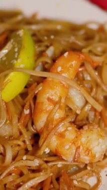 Çin Yeni Yılı. Erişteli karides ve etli Asya mutfağı. Tatil için akşam aile yemeği. Mutluluk ve iyilik için kırmızı zemin üzerinde hiyeroglifler olan altın sikkeler, yelpaze ve kartlar.