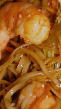 Çin Yeni Yılı. Erişteli karides ve etli Asya mutfağı. Tatil için akşam aile yemeği. Mutluluk ve iyilik için kırmızı zemin üzerinde hiyeroglifler olan altın sikkeler, yelpaze ve kartlar.