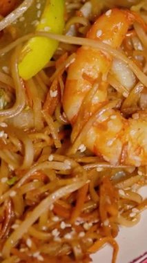 Çin Yeni Yılı. Erişteli karides ve etli Asya mutfağı. Tatil için akşam aile yemeği. Mutluluk ve iyilik için kırmızı zemin üzerinde hiyeroglifler olan altın sikkeler, yelpaze ve kartlar.