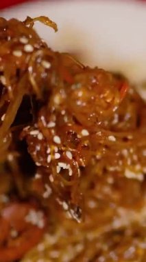 Çin Yeni Yılı. Erişteli karides ve etli Asya mutfağı. Tatil için akşam aile yemeği. Mutluluk ve iyilik için kırmızı zemin üzerinde hiyeroglifler olan altın sikkeler, yelpaze ve kartlar.