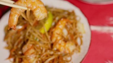 Çin Yeni Yılı. Erişteli karides ve etli Asya mutfağı. Tatil için akşam aile yemeği. Mutluluk ve iyilik için kırmızı zemin üzerinde hiyeroglifler olan altın sikkeler, yelpaze ve kartlar.