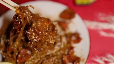 Çin Yeni Yılı. Erişteli karides ve etli Asya mutfağı. Tatil için akşam aile yemeği. Mutluluk ve iyilik için kırmızı zemin üzerinde hiyeroglifler olan altın sikkeler, yelpaze ve kartlar.