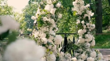 Gelin ve damadın düğün töreninden önce nehir kıyısında beyaz gül çiçeklerinin kemeri, romantik bir dekor. Yüksek kaliteli FullHD görüntüler