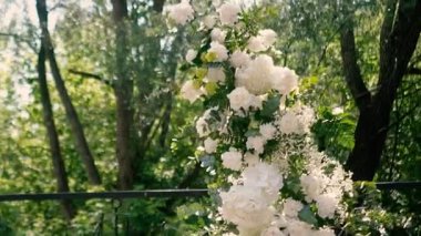 Gelin ve damadın düğün töreninden önce nehir kıyısında beyaz gül çiçeklerinin kemeri, romantik bir dekor. Yüksek kaliteli FullHD görüntüler