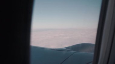 Ufuktan ve yüksek dağlardan karlı ve bulutlu bir görüntü. Seyahat ve tatil sırasında büyük bir yolcu gemisiyle gökyüzünde uçmak. Uçak penceresi ve kanadı havada. Yüksek kalite