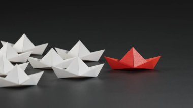 Farklı iş anlayışı. Yeni fikirler. Kağıt sanatı. Yaratıcı fikir. Liderlik konsepti, beyaz teknelere önderlik eden siyah lider teknesi. Siyah arka planda 3D görüntüleme..