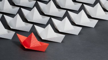 Farklı iş anlayışı. Yeni fikirler. Kağıt sanatı. yaratıcı fikir. Kırmızı lider botu, beyaz kayık kalabalığının önünde duruyor. Siyah arka planda 3 boyutlu görüntüler..