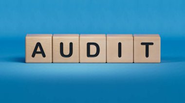 AUDIT iş sözcüğüyle tahta küp bloğu. Ahşap elementlere yakın plan, mavi arkaplanda 3D İş Konsepti.