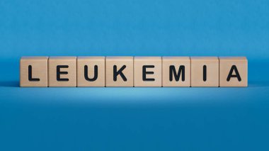 Doktor elinde kart tutuyor ve LEUKEMIa.sözcüğünü işaret ediyor ahşap elementlere yakın plan, mavi arka planda 3D İş Konsepti.