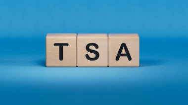TSA ile ahşap küp bloğu, vergilerle korunan yıllık metinler. Finansal, Yönetim, Ekonomi. Ahşap elementlerin kapatılması, mavi arka planda 3D İş Konsepti.