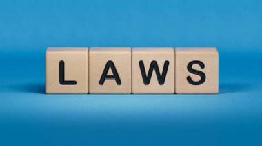 Kanunlar. Sözcük ahşap küplerle yazılmış. Ahşap elementlere yakın plan, mavi arkaplanda 3D İş Konsepti.