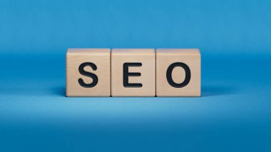 Sipariş edilen blok küpleri, web sitesi veya arama motoru optimizasyonu fikri hakkında SEO metni içeren ahşap blok küpleri hakkında SEO kelimesi. Mavi arkaplanda 3D iş kavramı.