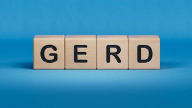 GERD kelimesi tahta küplere yazılır. Tıbbi konsept. Ahşap elementlere yakın çekim, mavi arka planda 3D iş konsepti..