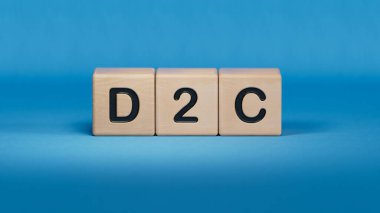 Üç taş küp, üzerinde D2C sözcüğü olan masalar - Acronim Doğrudan Tüketiciye. Ahşap elementlere yakın çekim, mavi arkaplanda 3D İş Konsepti.