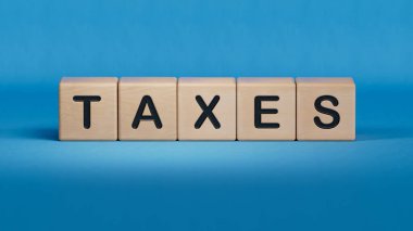 Tahta küp bloğu, vergilerle ilgili kelime. Ahşap elementlere yakın çekim, mavi arka planda 3D İş Konsepti..