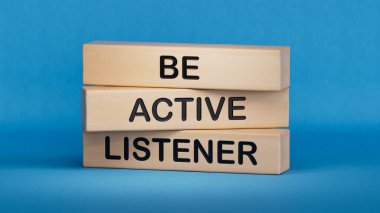 Aktif bir dinleyici sembolü ol. Sözcüklü tahta bloklar Etkin dinleyici olun. İş ve etkin dinleme kavramı. Mavi arkaplanda 3D kopyala.