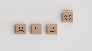 Müşteri hizmetleri değerlendirmesi, reytingler, geri bildirim, müşteri deneyimi ve memnuniyet anketleri. Beş yıldızlı işaretler ve beyaz arkaplandaki tahta küp bloğundaki mutlu yüzü gösteren eller..