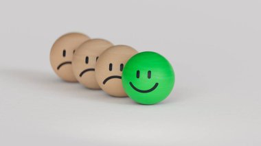 Üzgün yüzler ikonu ve gülen yüzler tahta top bloklarında. Pozitivizm, zihinsel refah kavramı. Beyaz arka planda üç boyutlu yüz ifadeleri..