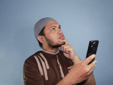 Şapkalı ve sakallı Asyalı bir adamın cep telefonu kullanışı.