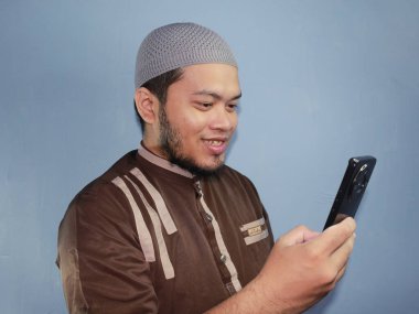 Şapkalı ve sakallı Asyalı bir adamın cep telefonu kullanışı.