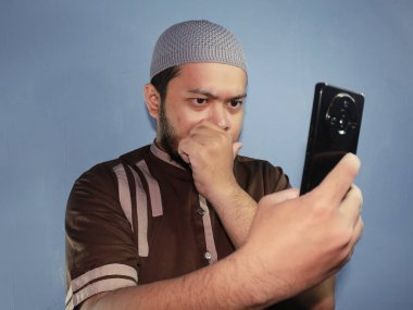 Şapkalı ve sakallı Asyalı bir adamın cep telefonu kullanışı.