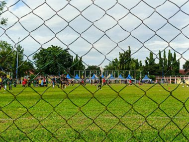 Banjarbaru-Endonezya, 12 Mei 2024: Çocuklar sahada top antrenmanı yapıyorlar, alanın kenarında telin ön plan fotoğrafı