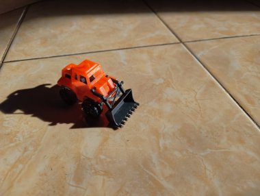 Turuncu çocuk oyuncağı buldozer, güneş ışığı...