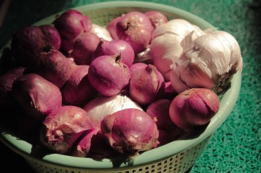 Güneş altında yeşil bir kapta salyangoz ve sarımsak.