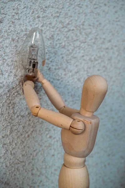 一个木制洋娃娃把灯泡当作一个协会来坚持自己的想法 — 图库照片