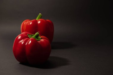 Siyah arka planda iki taze kırmızı biber.