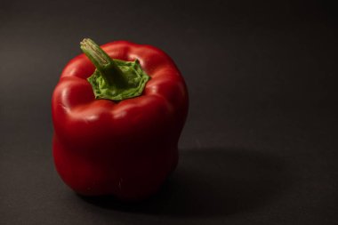 Koyu arkaplanda yeşil yapraklı taze kırmızı biber. sağlıklı vejetaryen yemekleri.