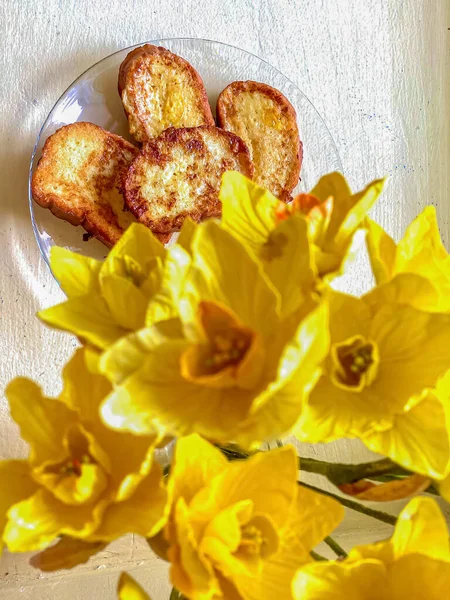 French toast with butter and yellow daffodils on white background