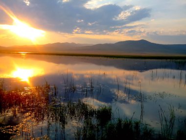 Gölde gün batımı. Dağ bozkırları korunan bölge