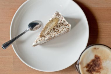 Tahta masada kahve fincanı olan bir parça tiramisu keki.