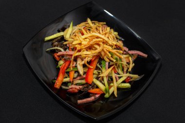 Siyah arka planda biftek ve sebzeli baharatlı salata