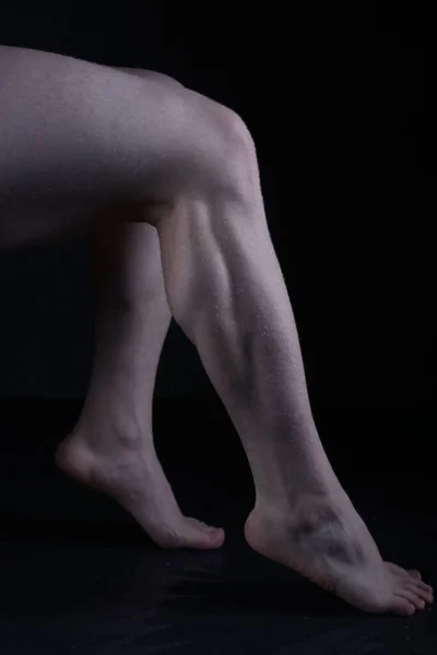 legs of a young man on a black background, studio shot