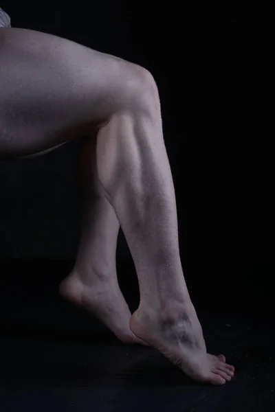 Legs of a young man on a black background. Studio shot.
