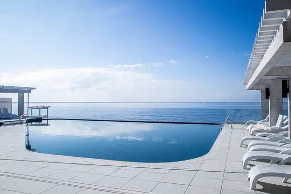 Swimming pool in luxury hotel with sea view and blue sky.