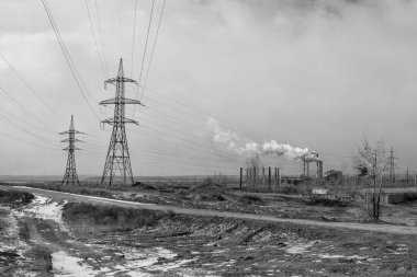 Alanın ortasındaki elektrik hattı. Elektrik santrali. Siyah beyaz fotoğraf.