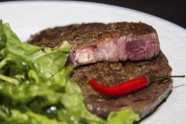 Marullu biftek ve beyaz tabakta kırmızı biber.