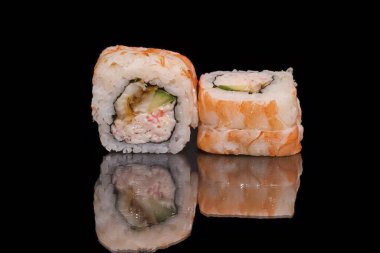 Siyah arka planda somon, salatalık ve krem peynirli suşi rulosu.