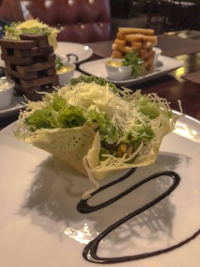 Marul ve peynirli salata bir restoranda beyaz tabakta